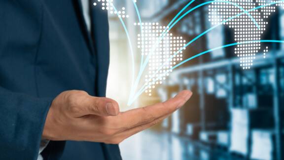 A persons hand overlaid with a 3D rendering of the world map