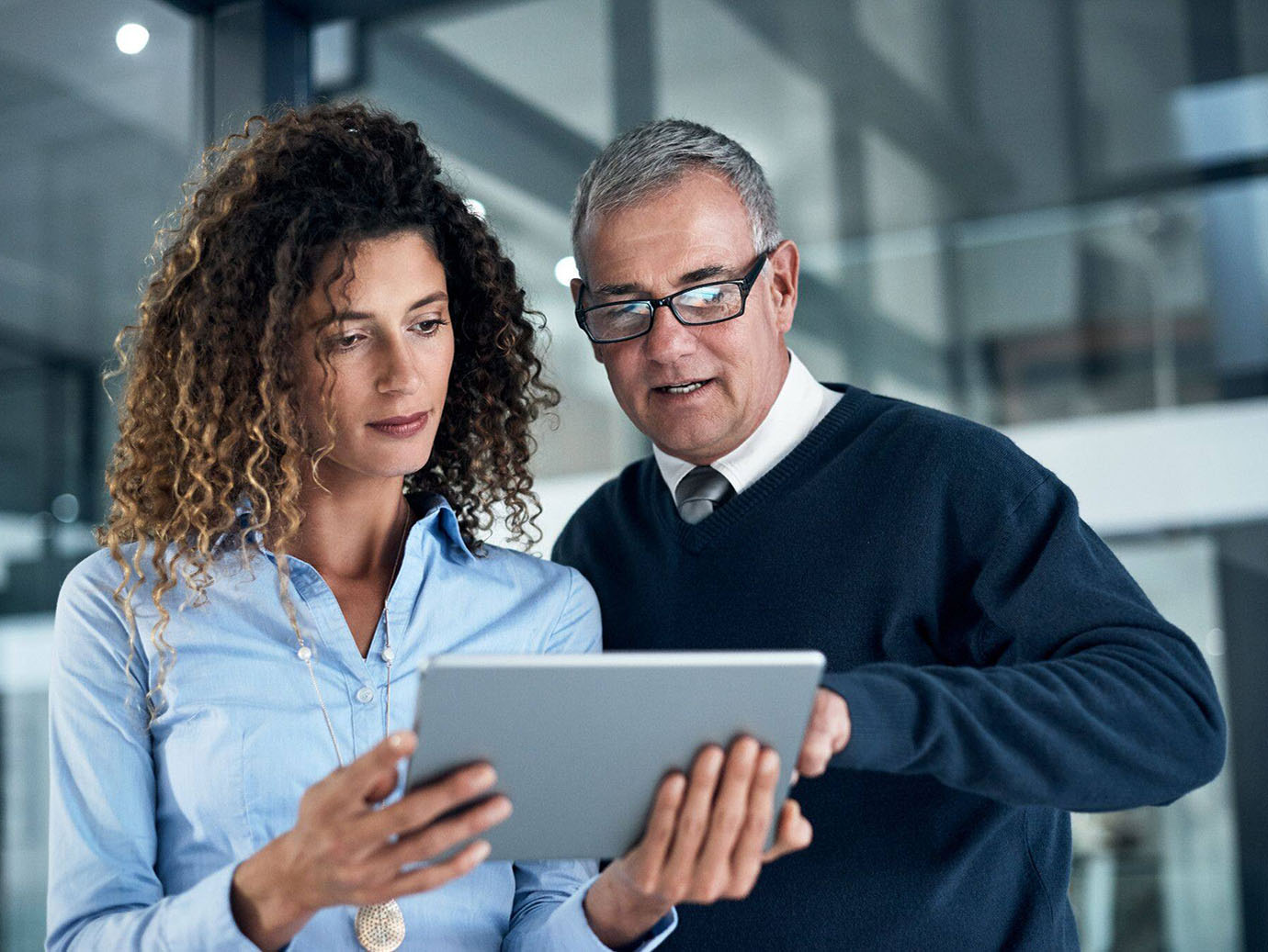 A male and a female employee discussing work while using a tablet