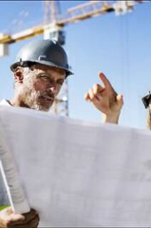 Two engineer in safety jackets having a discussion over a blueprint in an outdoor space