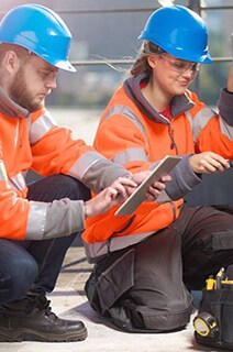 A man and a female engineer in safety suit inspecting a hvac device