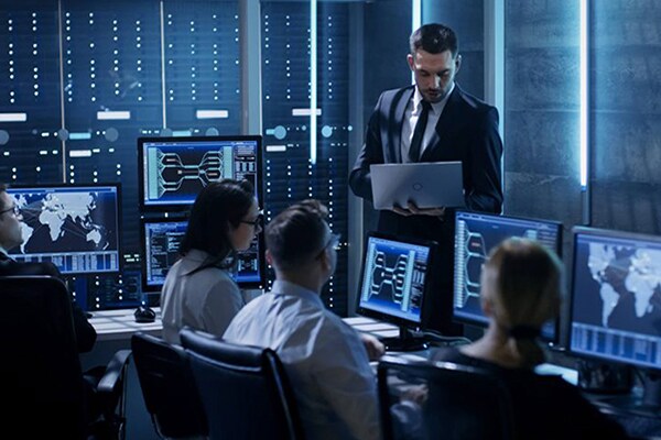 A man holding a laptop in his hands in a control room