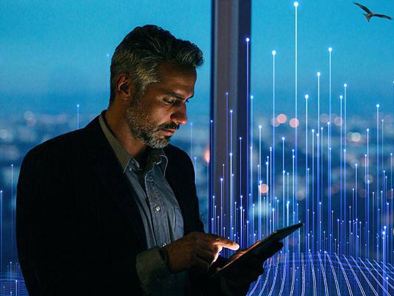 A man looking at a tablet standing in front of a window