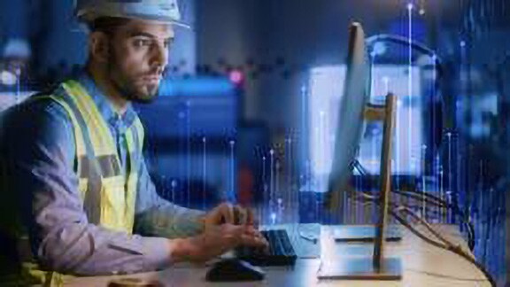 A maintenance engineer dressed in protective gear working on a monitor, with OpenBlue graphics in the foreground