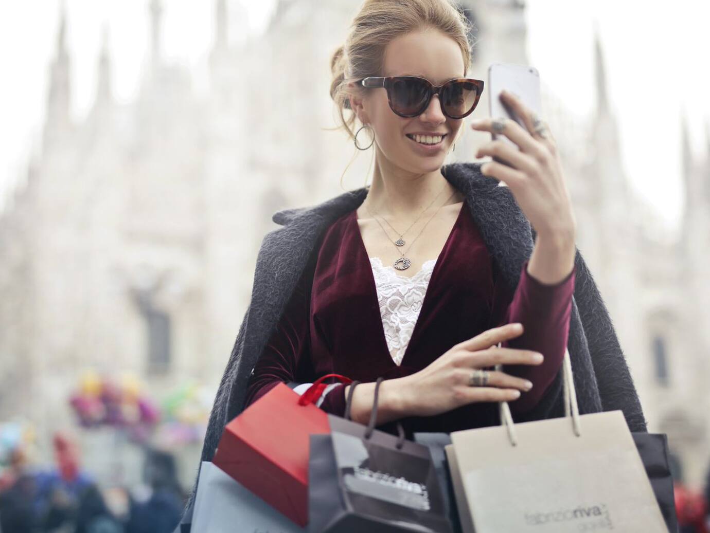 A woman holding shopping bags clicking a selfie