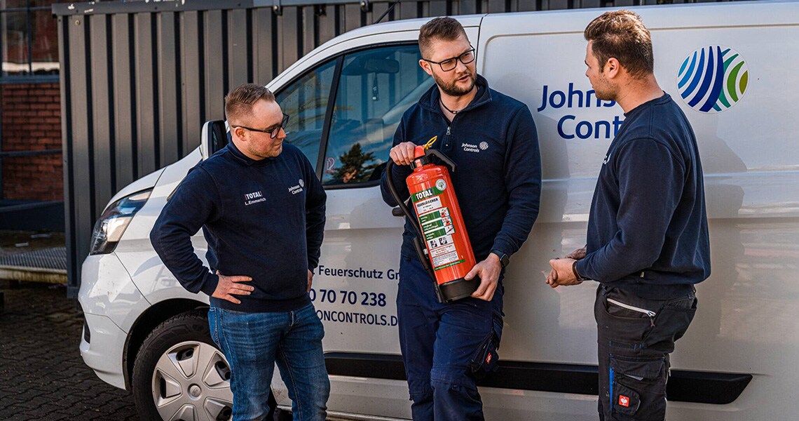 Johnson Controls engineers having a conversation while holding a Total fire extinguisher