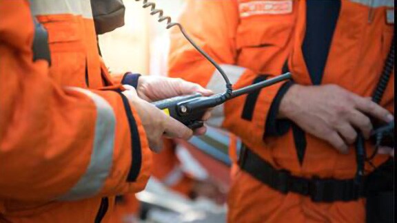 Close-up shot of a group of engineers in safety suits conversing with each other