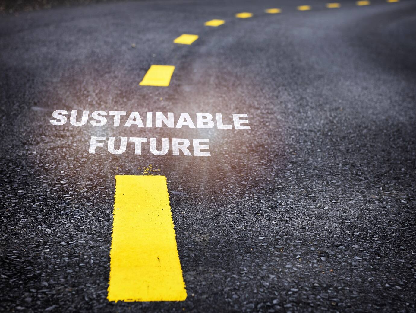 Yellow road markings on a road with the text 'Sustainable Future'