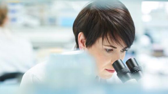 female-scientist-closely-looking-into-microscope