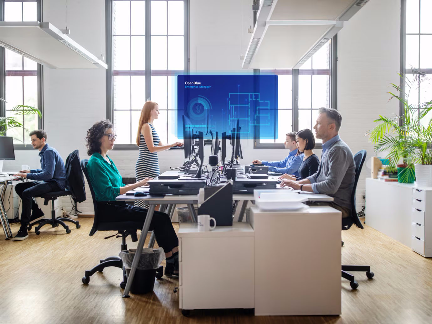Employees at work in an office, with a blue OpenBlue poster overlaid in the background