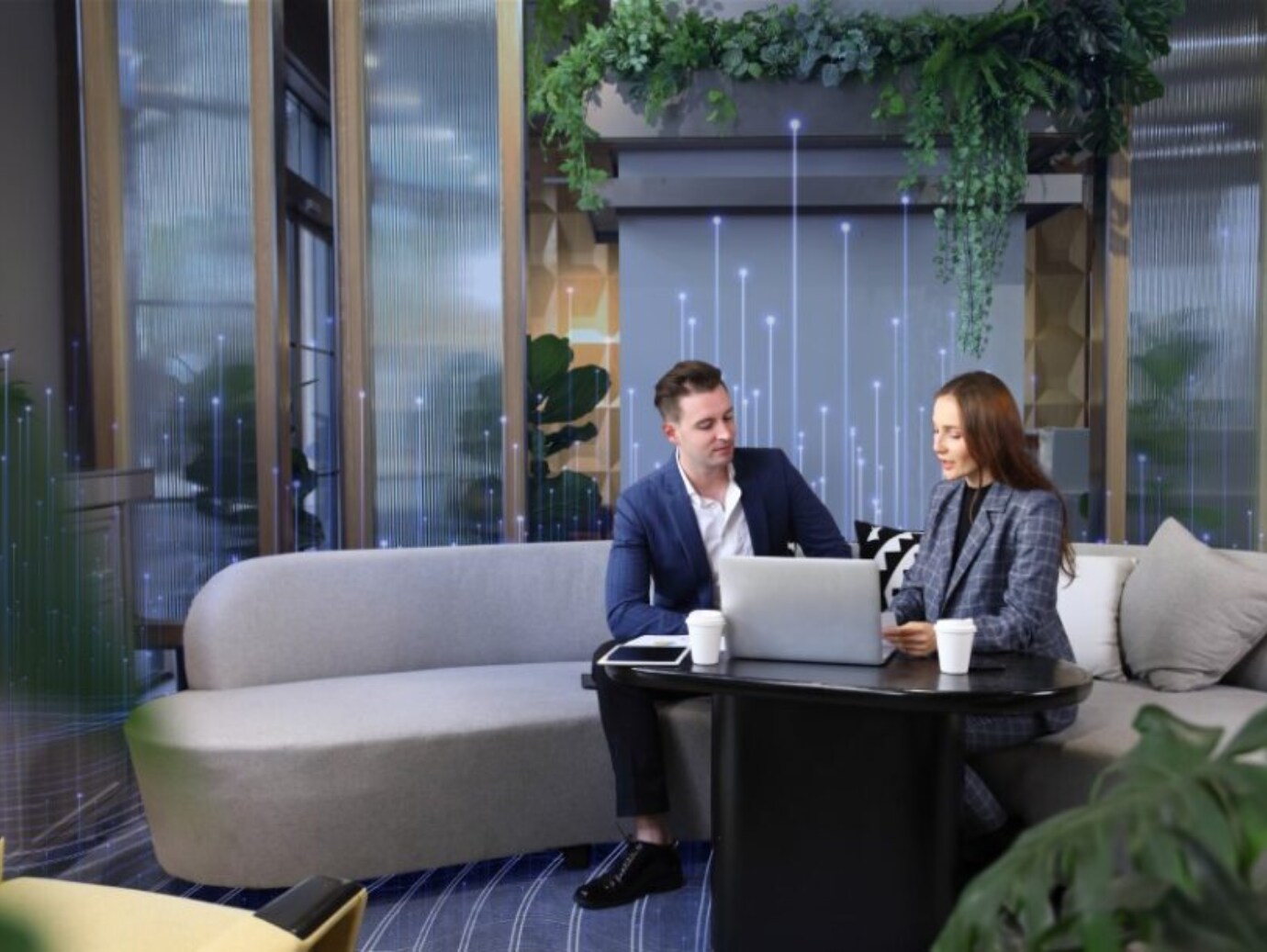 A man and woman sitting on a sofa and looking at a laptop in an office building