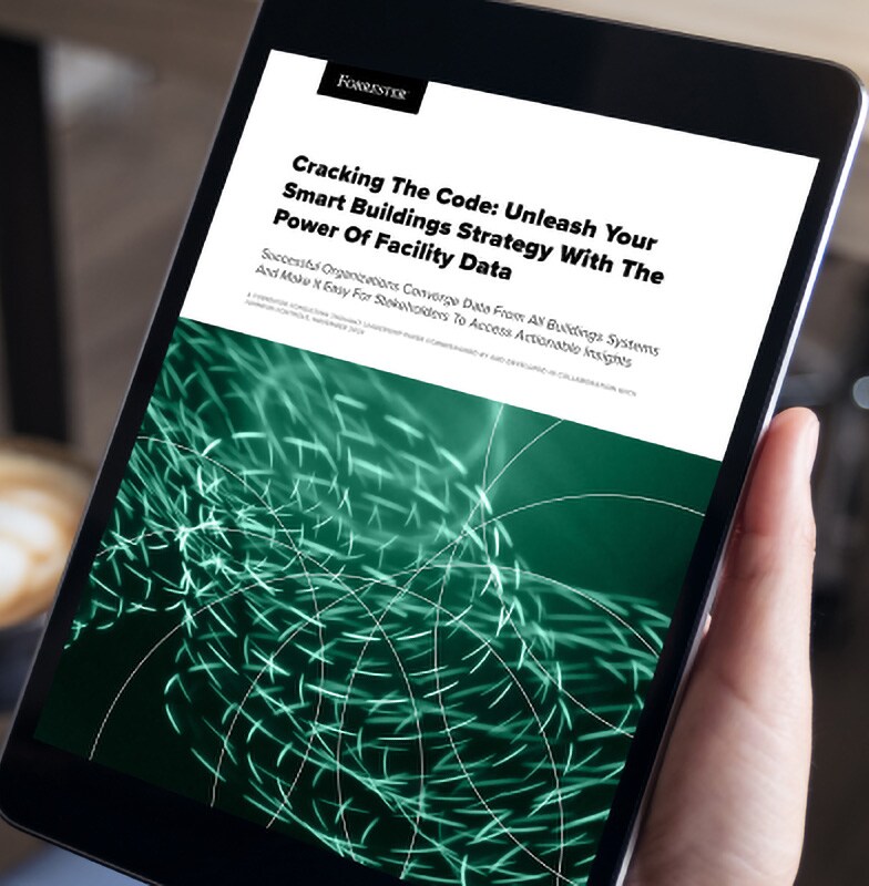 Close-up of a person holding a tablet displaying an article by Forrester about smart buildings